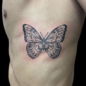 Elegant black and gray butterfly tattoo on ribs by Letitia Mortimer. Perfectly captures the beauty of nature.