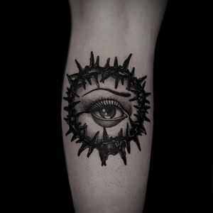 Discover the intricate details of this black and gray tattoo featuring thorns, eye, and eyebrow motifs by artist Lamat. Perfect for the lower leg.
