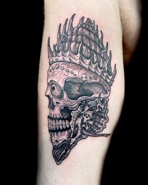 Black and gray tattoo featuring a skull wearing a crown, expertly done by Fernando Joergensen on the lower leg.