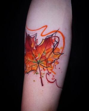 Vibrant watercolor leaf tattoo art on forearm, created by Aygul for a unique and beautiful look.