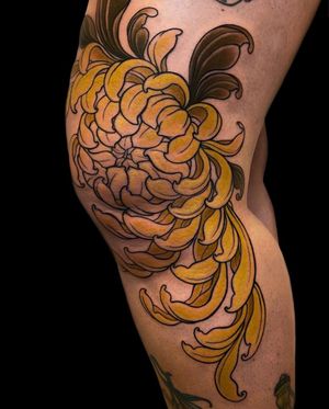 Immerse yourself in the beauty of a vibrant chrysanthemum flower expertly crafted by Edyta on your knee in a neo-traditional style.