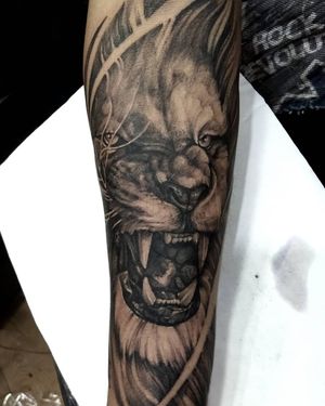 Experience the power of the wild with a stunning black and gray lion tattoo on your forearm. Realistic and illustrative, created by the talented artist Avi.