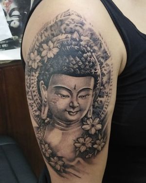 Stunning illustrative tattoo on the upper arm featuring a beautiful flower and Buddha, created by Avi.