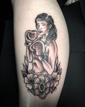 Beautiful fine line black and gray tattoo on lower leg featuring a woman with boxing gloves surrounded by delicate flowers, by Matthew Ono.