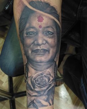 Stunning forearm tattoo featuring a beautifully detailed black and gray illustration of a woman with flowers by Avi.