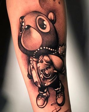 Unique blackwork tattoo by Cloto.tattoos featuring a bear, necklace, and doll motif on the forearm.