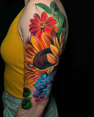 Vibrant watercolor flower design on upper arm by Cloto.tattoos. Beautiful and feminine illustration.
