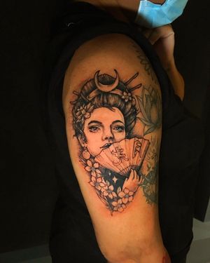 Embrace the elegance of a blackwork geisha surrounded by a traditional fan design, expertly inked by Frankie Brown.