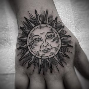This stunning black-and-gray fine line tattoo of a sun inside a circle is perfect for the hand. By talented artist Lamat.