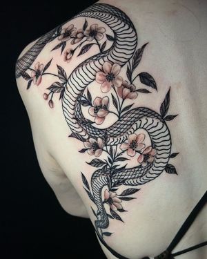 Intricate Japanese design by artist Fernando Joergensen, featuring a striking snake and delicate flower motif on the upper back.