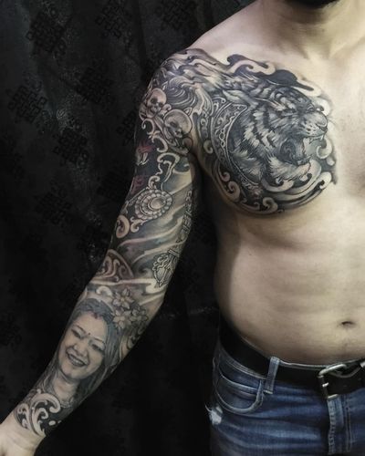 Get a stunning black and gray chest tattoo featuring a fierce tiger, creepy skull design, and intricate filigree patterns by Avi.