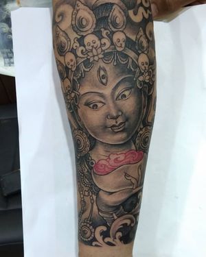A striking black and gray tattoo on the forearm featuring a woman with earrings and Kali motif by Avi.