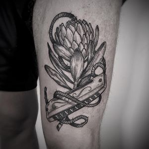 Exquisite black and gray fine line tattoo featuring a harmonica, flower, and leaf design, created by the talented artist Lamat.