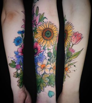 Vibrant and delicate watercolor flower tattoo on the forearm by Aygul, perfect for a pop of color.
