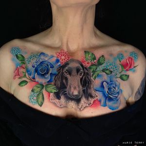 Incredible chest tattoo by Marie Terry featuring a lifelike dog and vibrant watercolor flower design.