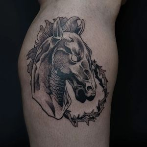 Elegant black and gray tattoo by Luca Salzano featuring a majestic horse surrounded by intricate thorns on lower leg.
