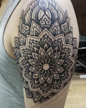 Avi's blackwork and dotwork design features an ornamental mandala pattern, creating a stunning and detailed tattoo on the upper arm.