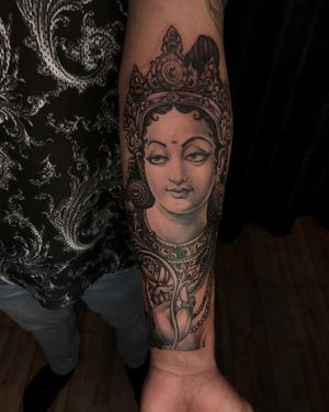 A stunning black and gray forearm tattoo featuring a patterned woman inspired by Kali, with intricate earrings, collar, and crown. Created by Avi.