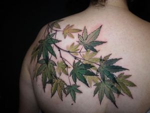 Beautiful leaf design in watercolor style on upper back by Aygul. A nature-inspired and vibrant tattoo choice.