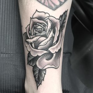 Get a stunning black and gray rose tattoo on your shin by expert artist Matthew Ono for a timeless and classic look.