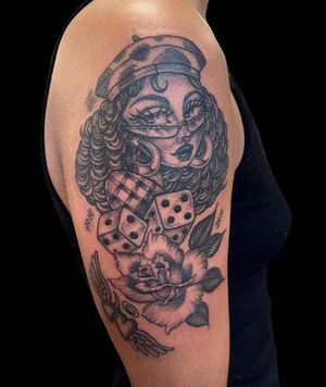 Beautiful black and gray upper arm tattoo of a chicano style woman with flowers, by Letitia Mortimer.