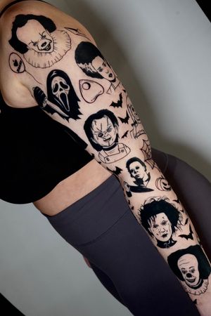 Get spooked with this blackwork sleeve tattoo featuring Chucky, a knife, It the clown, and a Ouija board by the talented Miss Vampira.