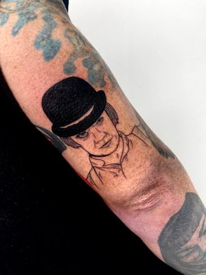 Experience the artistry of Miss Vampira with this blackwork illustrative tattoo of a man wearing a hat on your upper arm.
