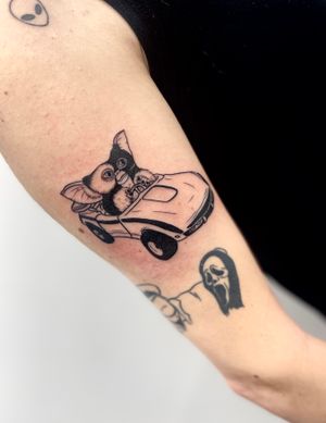 Unique blackwork anime tattoo of a car inspired by Gremlins, elegantly created by Miss Vampira on the upper arm.