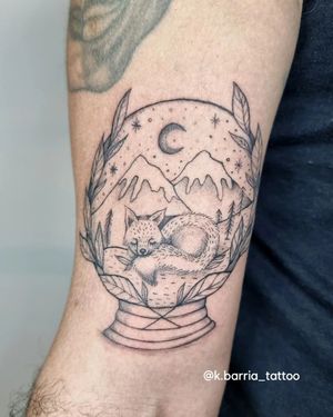 Unique tattoo by Katia Barria blending mountain, fox, and snow globe elements in a fine line style on the upper arm.