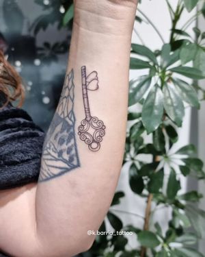 Exquisite forearm tattoo by Katia Barria featuring a delicate key motif in fine line style.