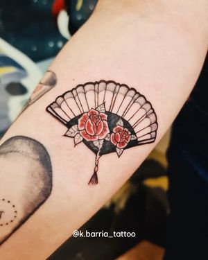 Elegant and delicate design by Katia Barria, combining floral elements and a fan motif in fine line style on the forearm.