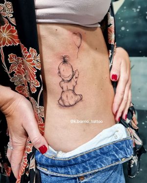 Celebrate new life with Katia Barria's delicate fine line tattoo featuring a baby and balloon motif on the ribs.