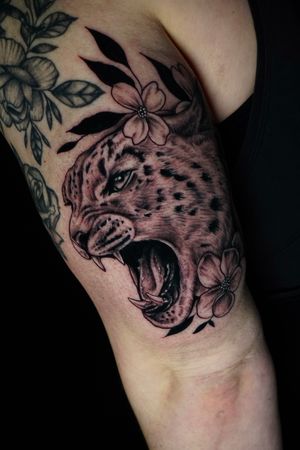 A stunning blackwork and illustrative tattoo of a leopard and flower, created by the talented artist Miss Vampira.
