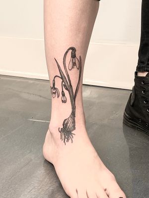 Beautifully detailed tattoo by Gifford Kasen featuring a combination of flowers and garlic, creating a unique and captivating design on the lower leg.