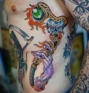 Vibrant neo-traditional design by Adam Ruff featuring a snake and hand motif on the ribs.
