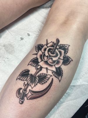 Fine line tattoo on lower leg by Adam Ruff, featuring a beautiful flower and a menacing scythe.