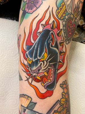 Incredible arm tattoo by Adam Ruff featuring a fierce panther surrounded by blazing fire in a neo-traditional style.