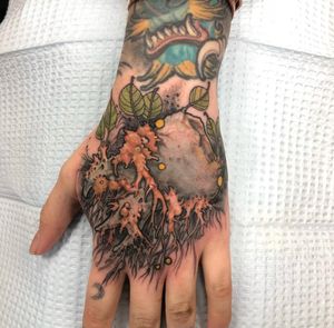Explore the beauty of nature with this detailed hand tattoo featuring a tree, flower, and leaf design by Gifford Kasen.