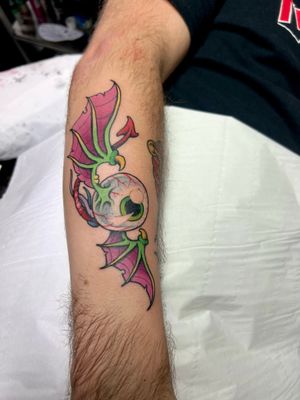 Vibrant new school design featuring a mesmerizing eye and intricate wings, beautifully crafted by the talented artist Adam Ruff on the forearm.