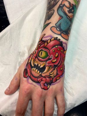 Vibrant new_school style illustration of a monster inked by Adam Ruff on the hand