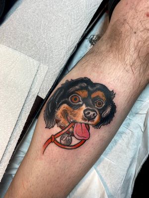 Get a unique neo traditional tattoo of a dog with a name on your lower leg, done by the talented artist Adam Ruff.