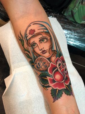 Get inked with a stunning traditional style nurse and rose design by tattoo artist Adam Ruff on your forearm.