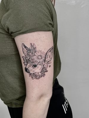 Elegant blackwork upper arm tattoo by Gifford Kasen, featuring a detailed deer and delicate flower design.