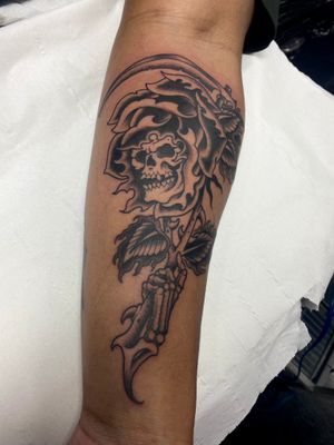 Unique design by Adam Ruff combining a beautiful rose with a dark grim reaper motif on forearm. Expertly crafted traditional style tattoo.