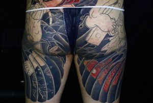 A stunning Japanese tattoo on the upper leg by artist Hansol Jung, featuring a graceful koi fish swimming among vibrant maple leaves.