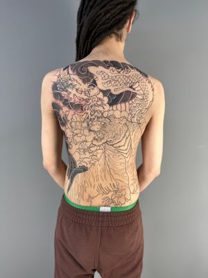 Intricately detailed back tattoo by Hansol Jung featuring a fierce tiger and mystical dragon inspired by Japanese art.