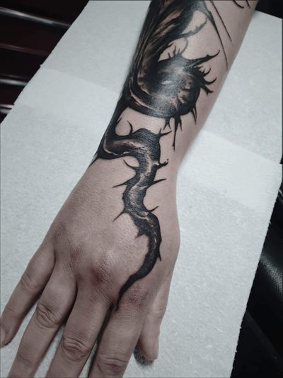 Bold black and gray dragon motif skillfully inked on forearm by Bellatrix Tattoo artist Rachel Aspe.
