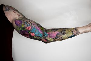 A stunning floral sleeve tattoo featuring a detailed flower motif by the talented artist Gifford Kasen.