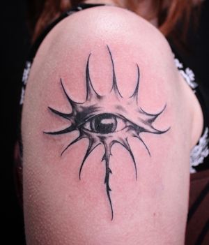 Unique black and gray design by José featuring intricate patterns and a lifelike eye on upper arm.