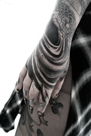 Get mesmerized by this black and gray snake and pattern design on your hand by Rachel Aspe at Bellatrix Tattoo.